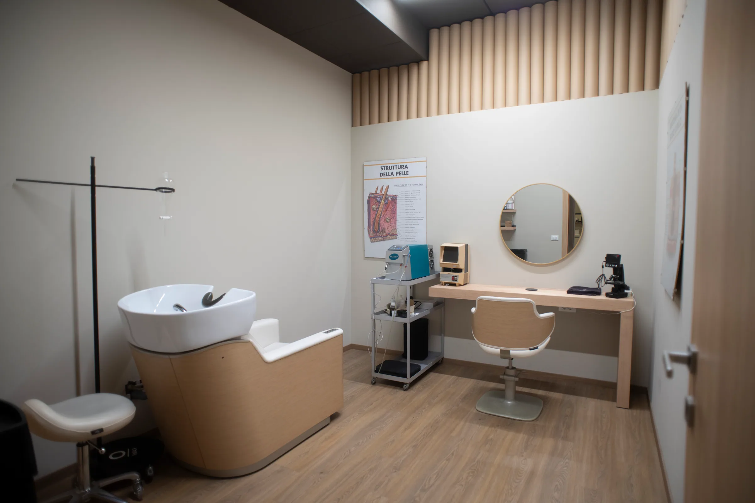 La cabina di tricologia con lavatesta, specchio tondo e poster sulla struttura della pelle