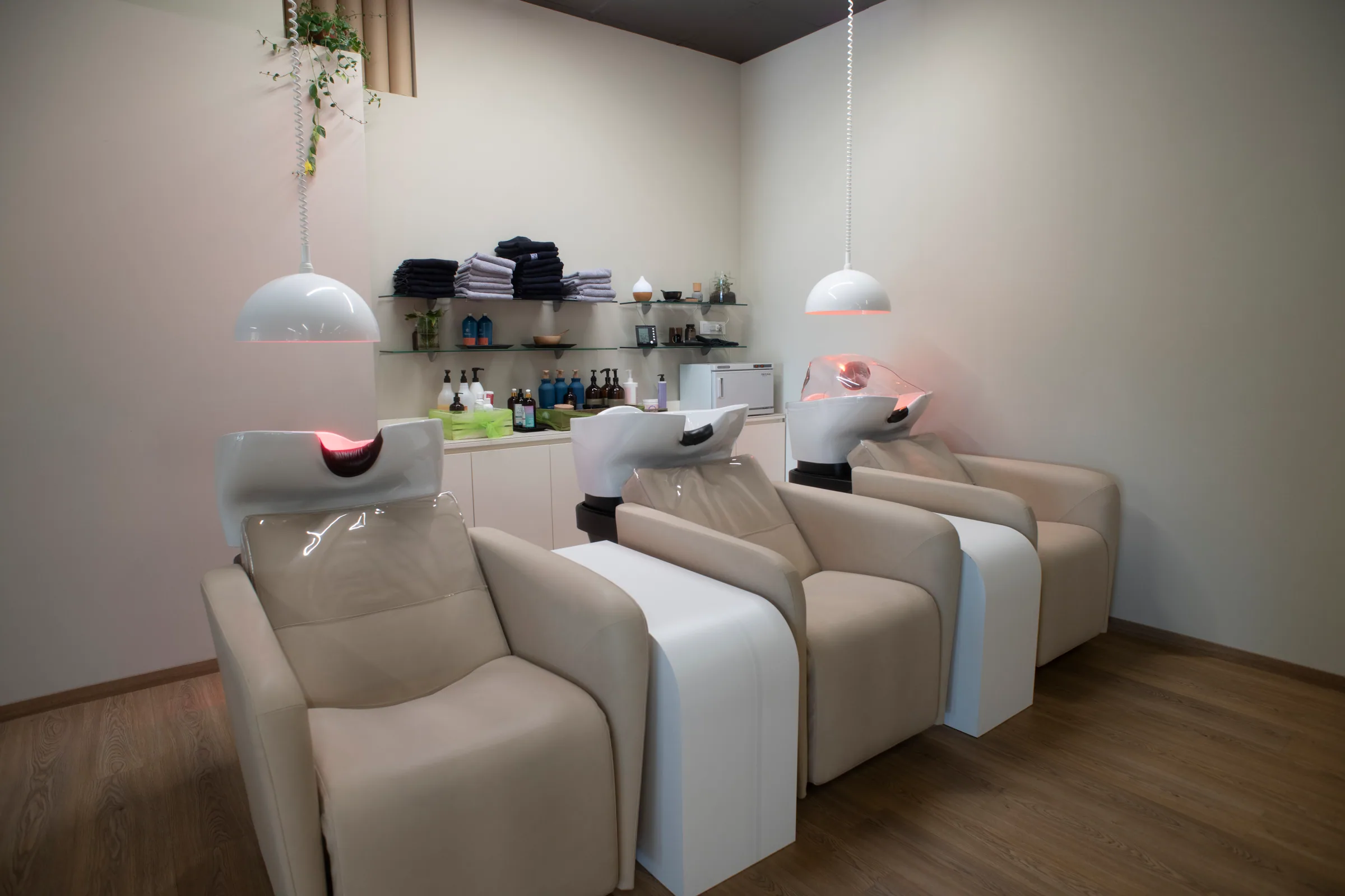 Le poltrone lavatesta della zona head spa con le lampade a luce rossa accese