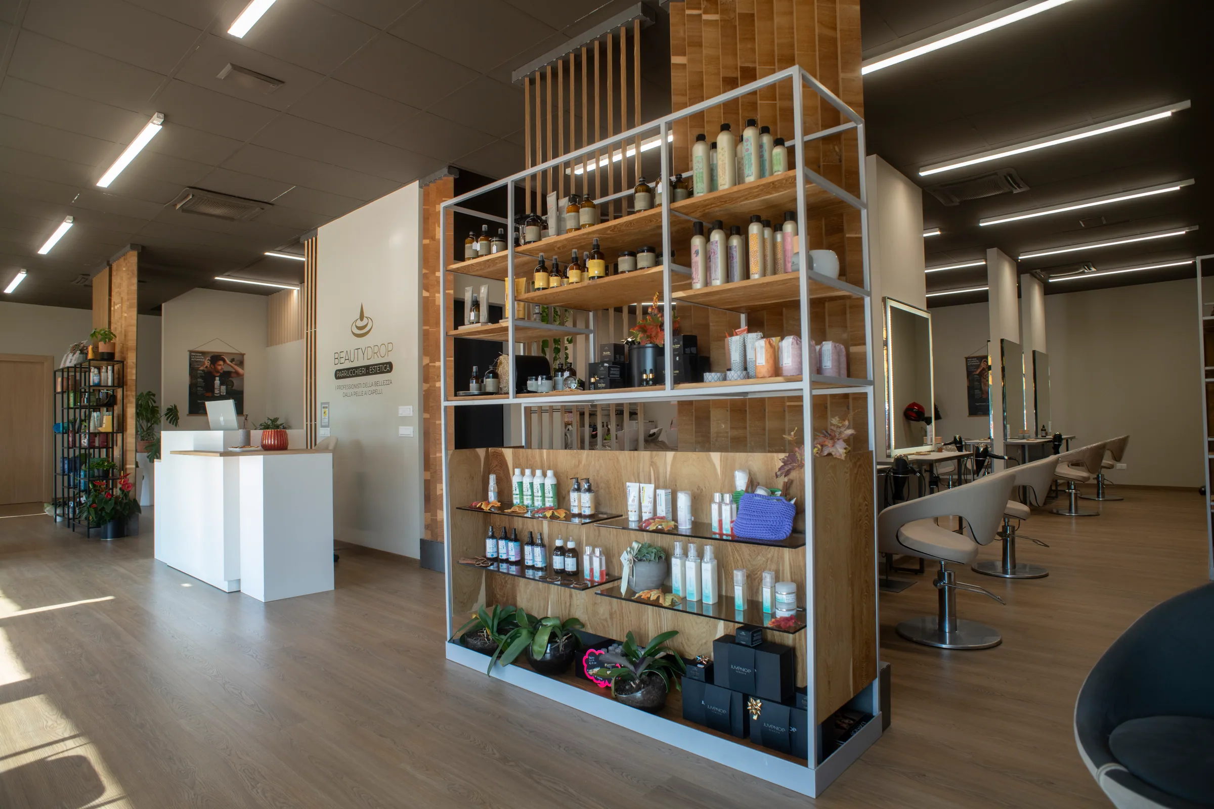Lo scaffale centrale del salone con i prodotti in vendita, la reception e il logo BEAUTYDROP sulla parete