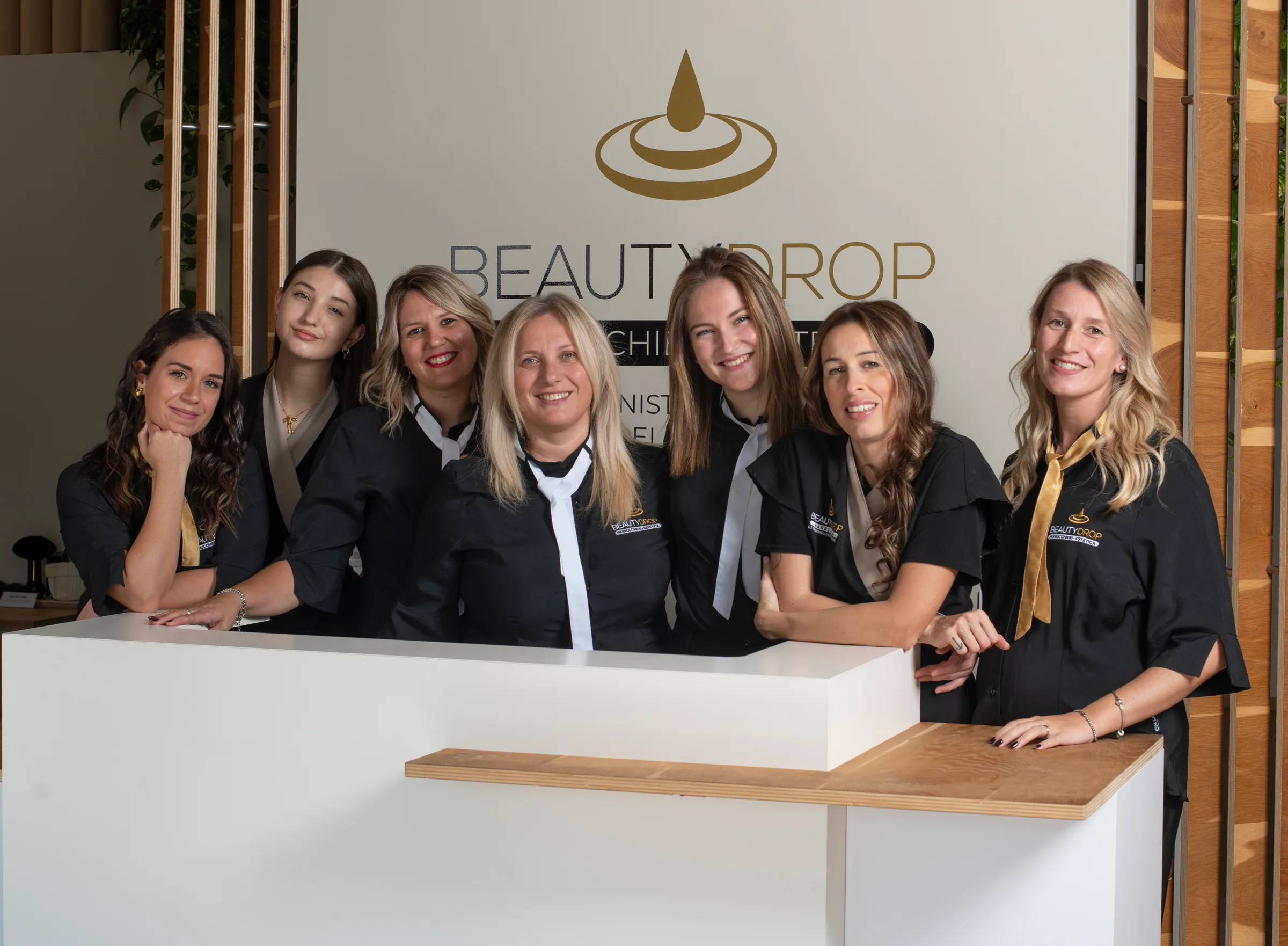 Il team BEAUTYDROP al completo, sorridente dietro il bancone della reception con il logo alle spalle
